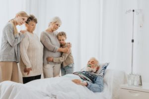 family gathers around the bed of a man who suffered a wrongful death in a nursing home, so they will file for a wrongful death settlement